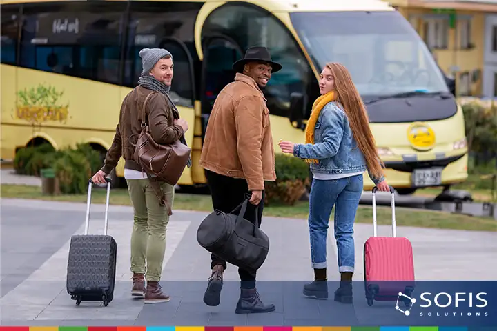 Tres personas caminando hacia un autobús con maletas y bolsos